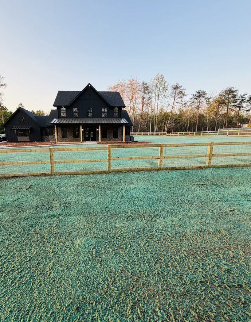 Farmhouse with wooden fence and freshly hydroseeded yard